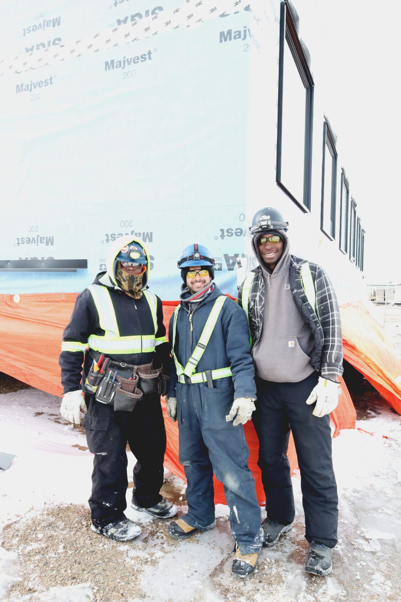 3 constructions workers standing Infront of a modular home.