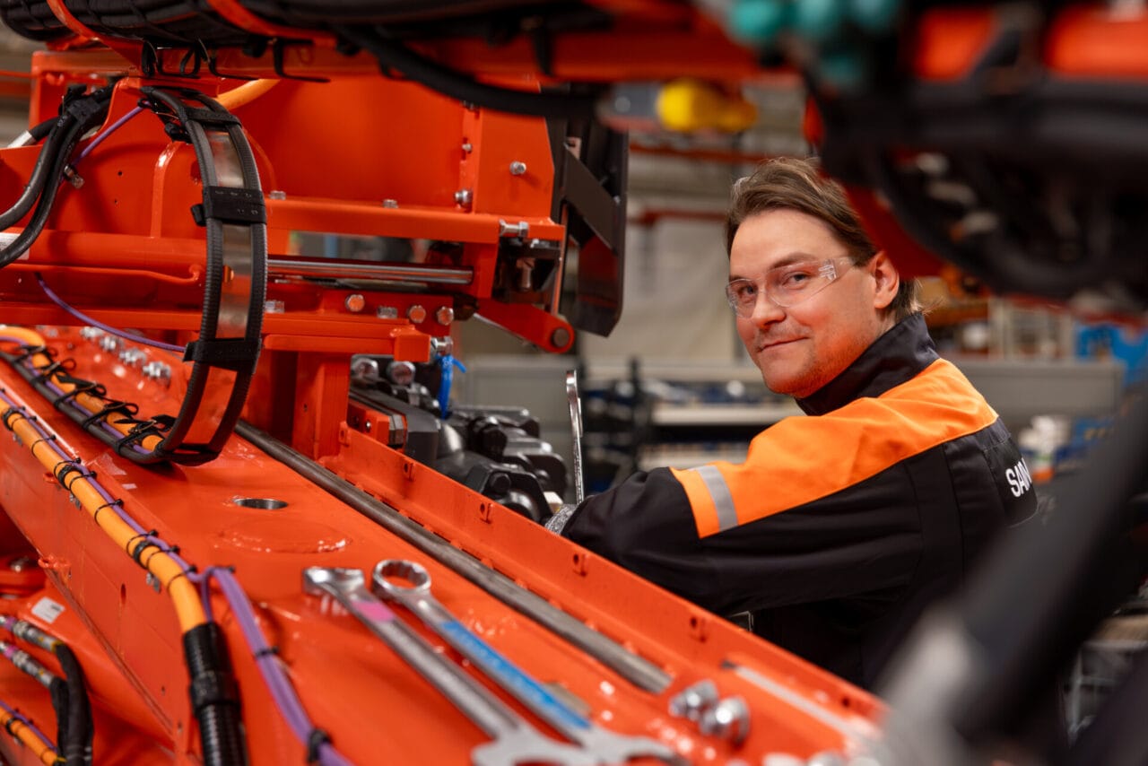 Close up of a worker assembling a piece of mining equipment in a manufacturing facility.