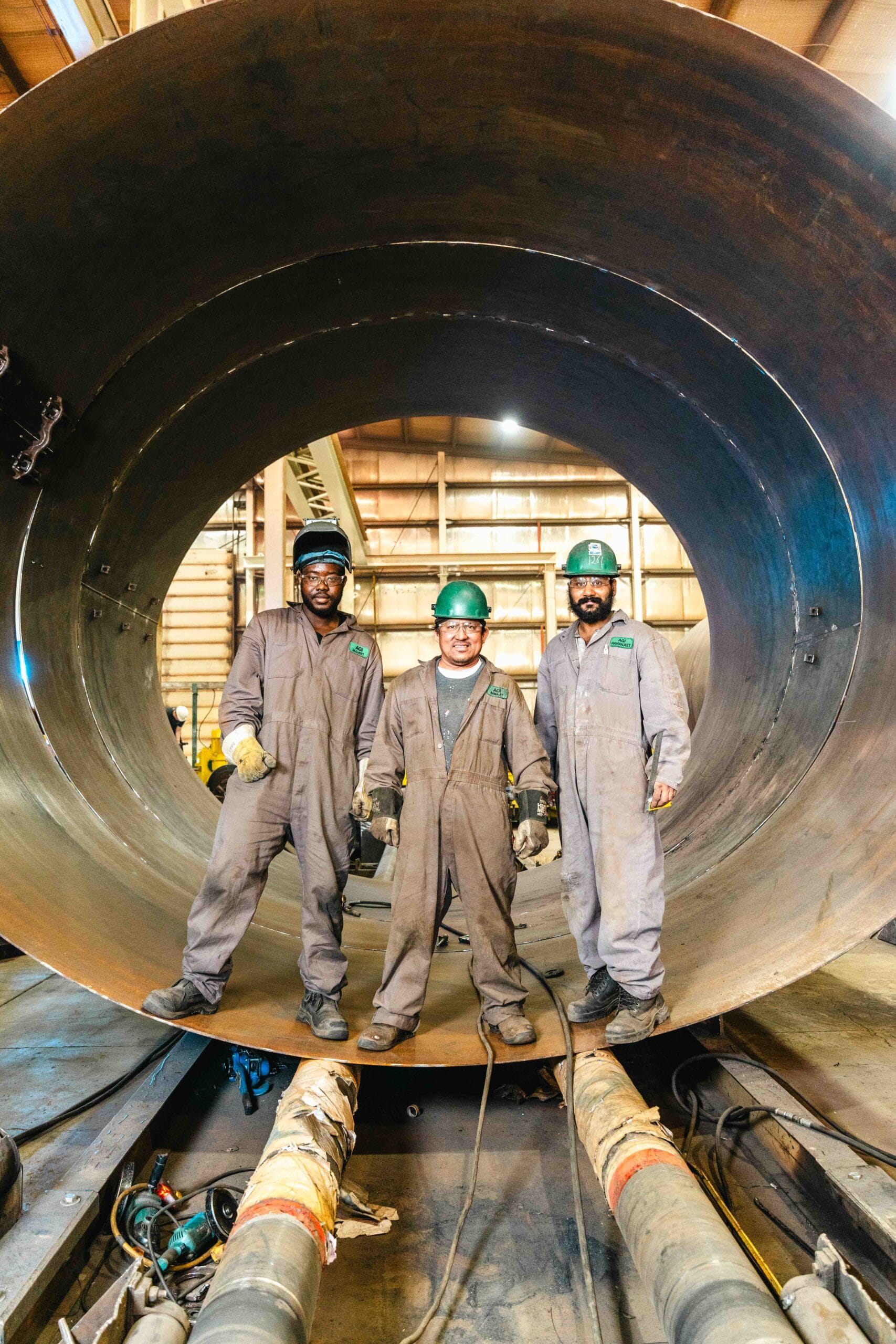 3 welders stand in a manufacturing shop. showcasing manufacturing in Saskatchewan.