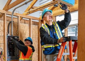 An electrician installs electrical wiring inside a new home under construction.