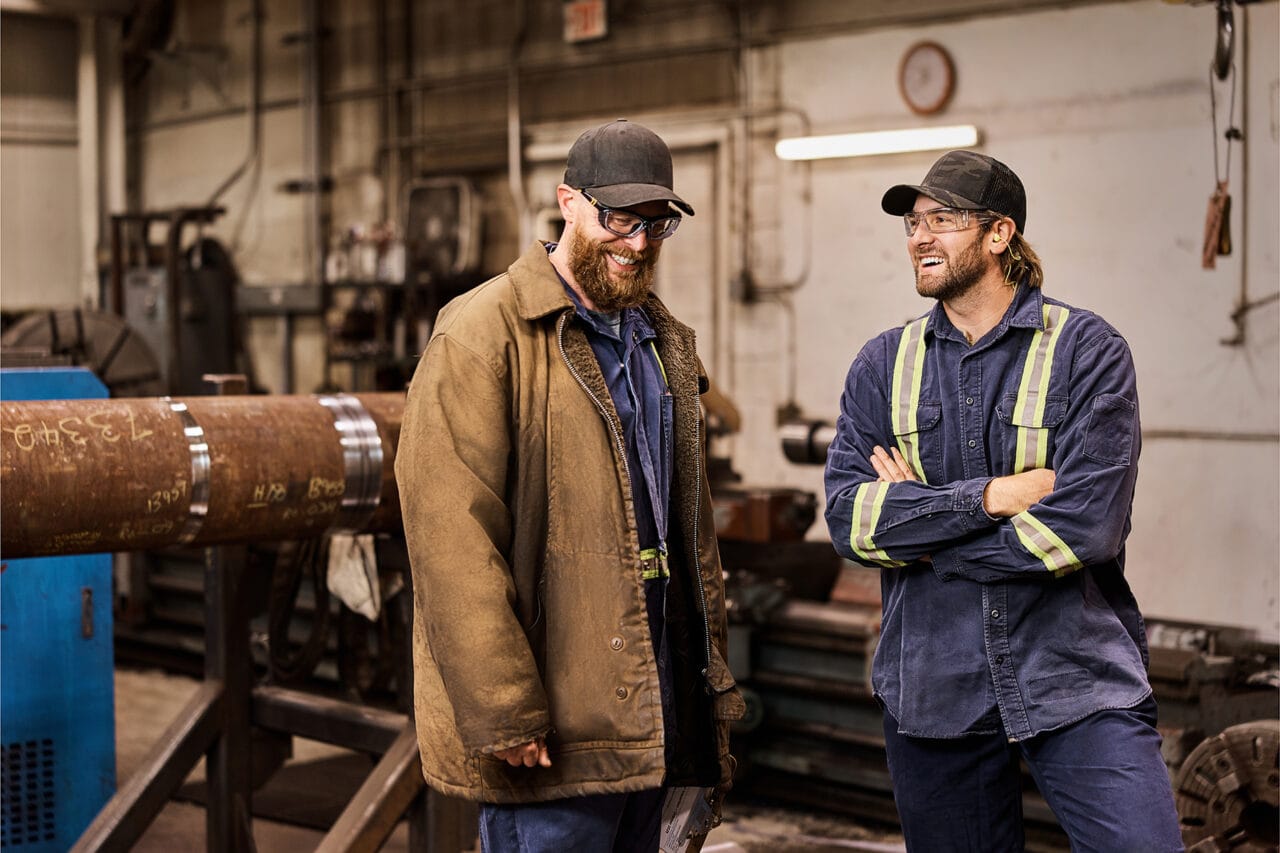 Two men talking in a manufacturing work shop.